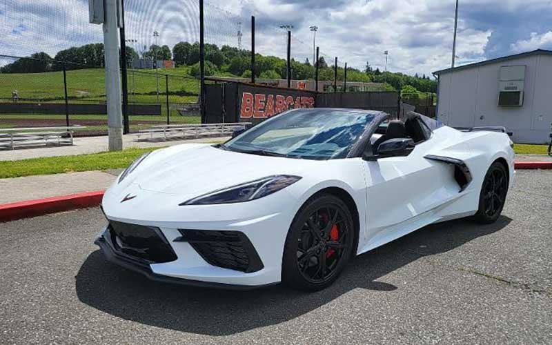 A white Chevy Corvette parked in front of Monroe Hight School